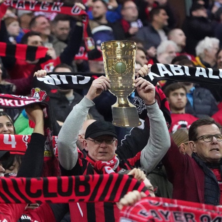 Ein Leverkusen-Fan streckt ein Bild des DFB-Pokals in die Höhe