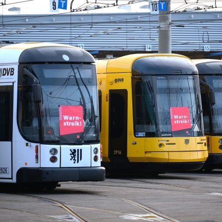 Straßenbahnen der Dresdner Verkehrsbetriebe stehen mit Warnstreik-Plakaten beklebt im Betriebshof