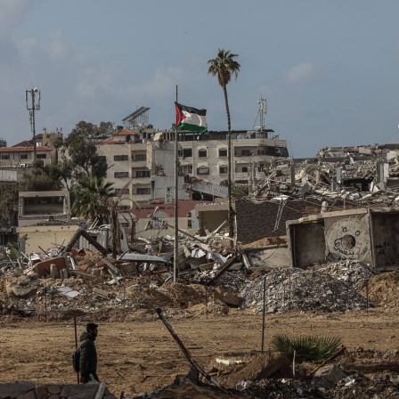 Palästinenser läuft im Gaza-Streifen an zerstörten Gebäuden entlang