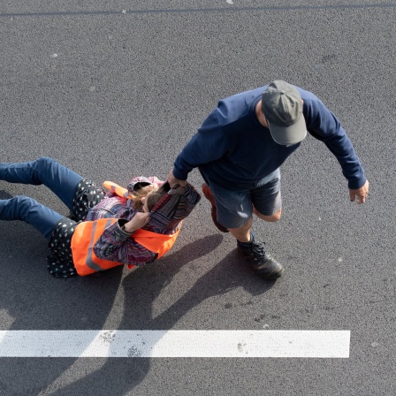 Ein Autofahrer schleift einen Demonstranten über eine Straße
