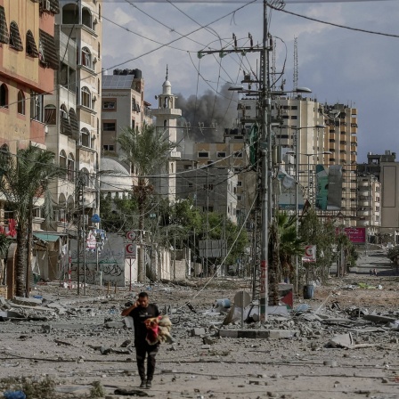 Ein Mann läuft über eine von Raketeneinschlägen zerstörte Straßen im Süden des Gazastreifens. 