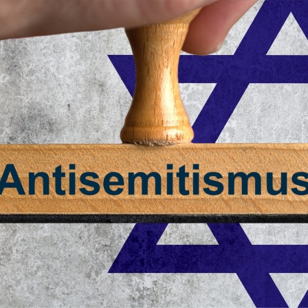 Stempel mit der Aufschrift &#034;Antsemitismus&#034; vor einer jüdischen Flagge