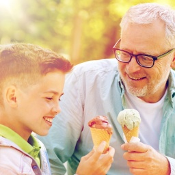 Ein Enkel isst mit seinem Opa ein Eis.