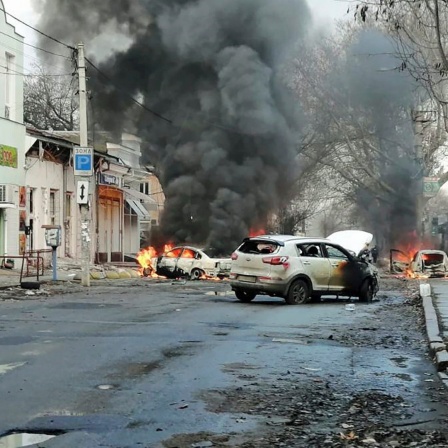 Autos brennen und Rauch steigt auf, nachdem ein russischer Raketenangriff das Stadtzentrum der südukrainischen Stadt Cherson getroffen hat.