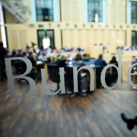 Die Abgeordneten sitzen bei der Plenarsitzung im Deutschen Bundesrat (Aufnahme durch eine Glascheibe).
