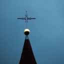 Ein Kreuz auf einer Kirchturmspitze.