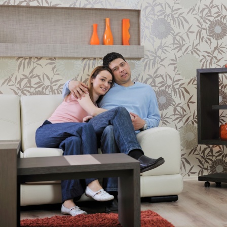 Junges Paar sitzt auf einer Couch, modernes Wohnzimmer.