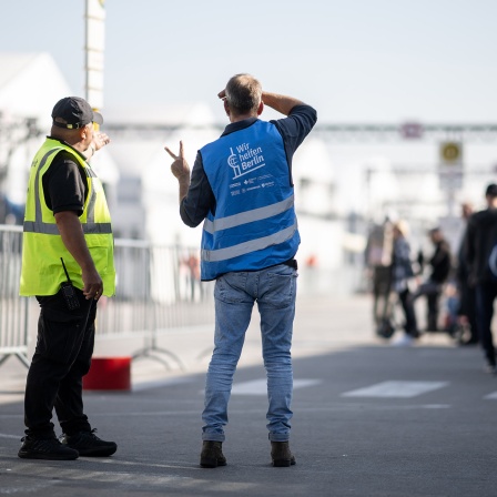 Helfer und Sicherheitskräfte stehen in der Notunterkunft für Geflüchtete am ehemaligen Flughafen Tegel.