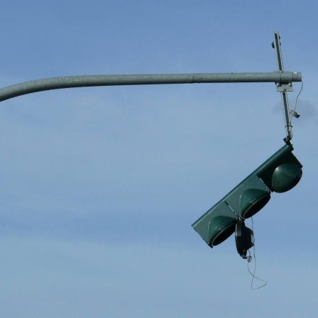 Nach einer Kollision ist eine Ampel kaputt und außer Betrieb. Sie hängt am Mast. 