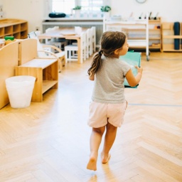 Ein Kind, was von hinten zu sehen ist, läuft stürmisch durch einen Raum im Kindergarten.