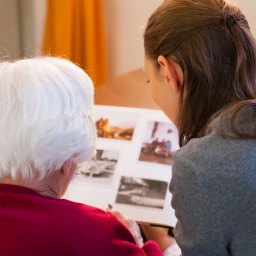 Enkelin schaut mit ihrer Großmutter ein Fotoalbum an