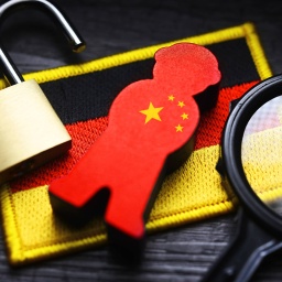 FOTOMONTAGE, Spion-Figur mit China-Fahne auf der Fahne von Deutschland, Symbolfoto chinesische Spionage