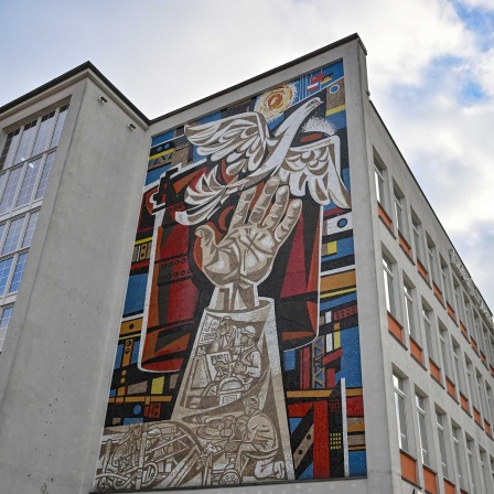 An einer Fassade in Eisenhüttenstadt ist ein großes Mosaik-Kunstwerk von Walter Womacka (1925 - 2010) zu sehen