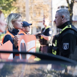 Aktivisten und Aktivistinnen stehen während einer Laufblockade der Klimaschutzgruppe Letzte Generation auf der Bornholmer Straße am 21. September vor Polizeibeamten.
