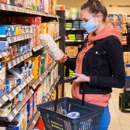 ILLUSTRATION - Eine Frau mit Mundschutz-Maske kauft in einem Supermarkt ein (gestellte Szene). 