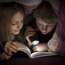 Brother and sister reading book under a blanket PUBLICATIONxINxGERxSUIxAUTxHUNxONLY SARF002302