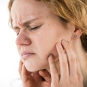 Eine Frau leidet unter Kieferschmerzen (gestellte Szene).