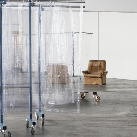 Blick in das experimentelle Live-Kunstwerk „Scalable Skeletal Escalator“ der in Berlin lebenden Künstlerin Isabel Lewis in der Kunsthalle Zürich, Schweiz. Sichtbar sind Folien als Raumtrenner und ein Sessel.
