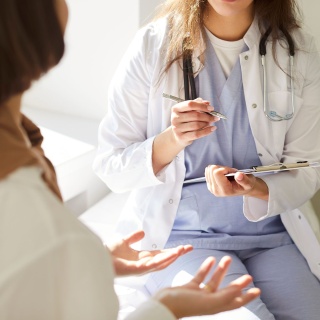 Eine Hausärztin spricht mit einer Patientin und macht sich Notizen. 
