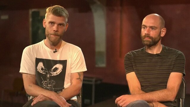 Zwei Männer sitzen auf der Bühne in einem Kinosaal in einer Interviewsituation.
