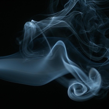 Rauch einer Zigarette steigt gegen schwarzen Hintergrund auf