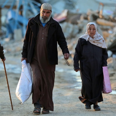 Menschen gehen an zerstörten Gebäuden im Flüchtlingslager Al-Maghazi im Zentrum des Gazastreifens im Zentrum des Gazastreifens vorbei.