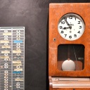 Symbolbild zur Arbeitszeiterfassung. Eine Uhr hängt an der Wand, daneben Karten zur Zeiterfassung der Arbeitsstunden