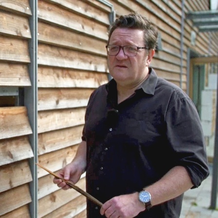 Martin Karolczak, Geschäftsführer GWS St. Pauli, steht nach einem rechten Angriff vor der Holzfassade der Kinder- und Jugendeinrichtung Hexenberg mit einem Stück der Wand in der Hand.