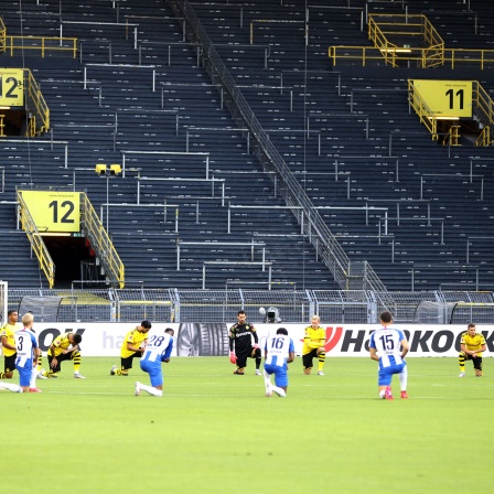 Spieler von Borussia Dortmund und Hertha BSC knien vor dem Anpfiff.