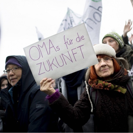 Eine ältere Klimaaktivistin hält auf einer Demonstration ein Schild mit "Omas für die Zukunft".