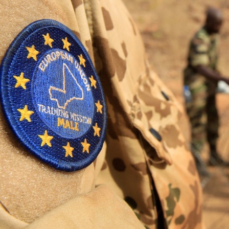 Abzeichen der EU-Ausbildungsmission am Oberarm eines Bundeswehrsoldaten. Im Hintergrund malische Soldaten.