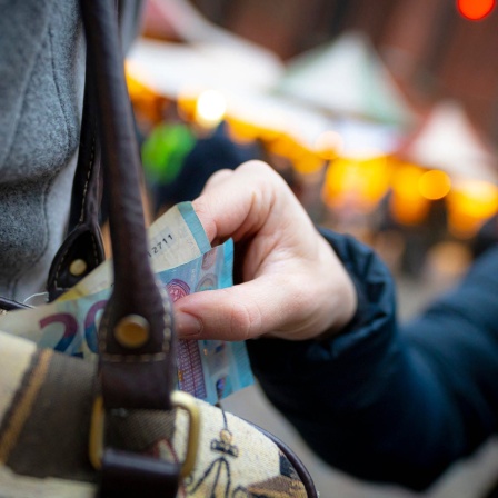 Taschendiebstahl: Eine Hand zieht Geldscheine aus einer Handtasche