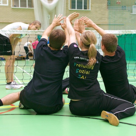 Jugendliche spielen Sitzvolleyball mit Menschen mit Behinderung. Seit 20 Jahren können Jugendliche auch in Sportvereinen ein freiwilliges soziales Jahr machen.