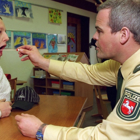 Ein Polizist nimmt am 9.4.1998 in der Grundschule von Strücklingen (Kreis Cloppenburg) einem jungen Mann eine Speichelprobe mit einem Wattestäbchen. 