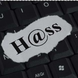 Ein Papierschnipsel mit dem Schriftzug "H@ss"l liegt auf einer Computertastatur.