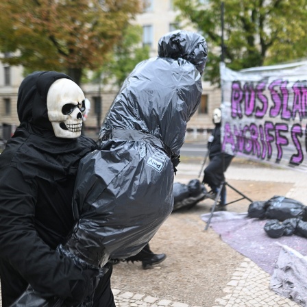 Ein als Tod verkleideter Demonstrant trägt einen symbolischen Leichensack