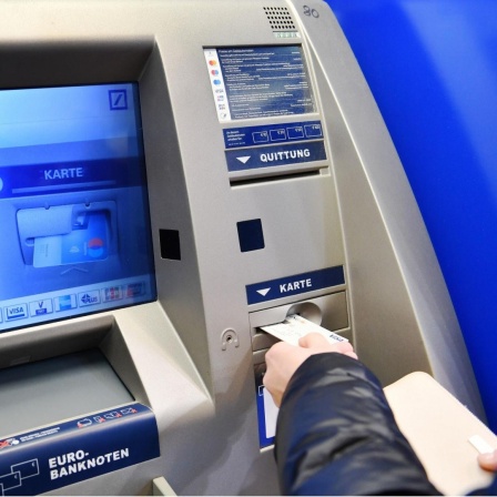Jemand führt eine Bankkarte in einen Geldautomaten ein.