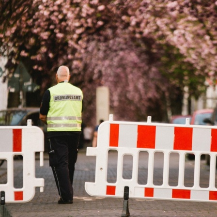 Ein Mitarbeiter des Ordnungsamt Bonn steht vor einer Absperrung.