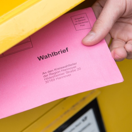 Ein rosa Wahlbrief wird in einen Briefkasten geworfen