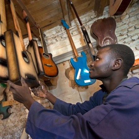 Justin Bashimbe sieht sich Gitarren in der Werkstatt an