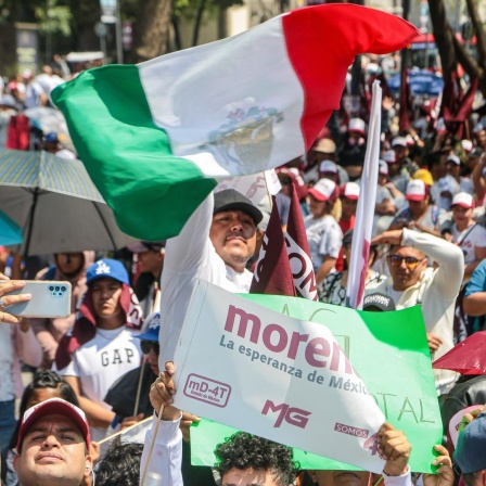 Ein Unterschützer der mexikanischen Präsidentschaftskanidatin Claudia Sheinbaum hält während einer Kundgebung in Mexiko City eine mexikanische Fahne in die Höhe.