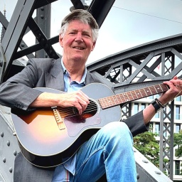 Eddy Winkelmann sitzt mit seiner Gitarre auf der Brücke