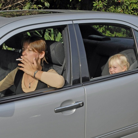 Frau raucht im Auto mit Kind