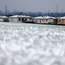 Nach nächtlichem Schneefall liegt eine weiße Decke auf Feldern und Dächern in einem Neubaugebiet im Ort Neufreimersdorf bei Köln.
