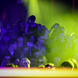 Menschen stehen in blau grünem Licht in einem Club. Viele tragen schwarze Kleidung und sportliche Sonnenbrillen. | Bild: picture alliance / SZ Photo | Leonhard Simon