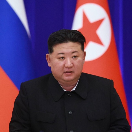 Porträt von Kim Jong Un mit der nordkoreanischen und der russischen Flagge im Hintergrund.