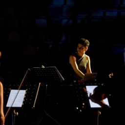 Die Komponistin Aida Shirazi steht mit MusikerInnen auf einer Bühne.