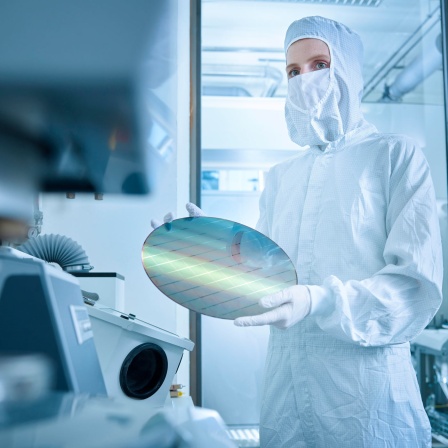 Eine Ingenieurin hält einen Halbleiterchip in einem Labor in der Hand (Bild: picture alliance / Westend61)