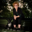 Zora del Buono hockt auf der Lehne einer Parkbank, zu ihren Füßen sitzt ihr Hund.