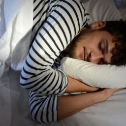 Ein Mann im Ringelshirt liegt im Bett und schläft.